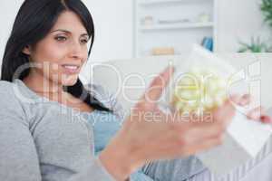 Woman sitting on a couch while opening a gift box