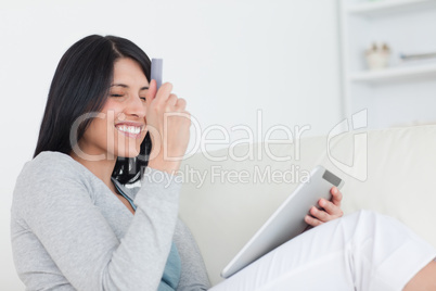 Smiling woman holding up a credit card and a tablet