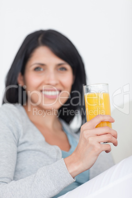 Woman smiling while holding a glass of orange juice