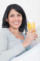 Woman smiling while holding a glass full of orange juice