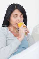 Woman closing her eyes while drinking from a glass of orange jui