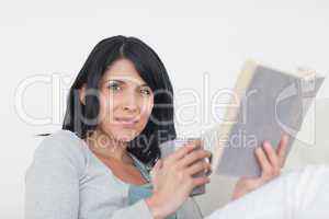 Woman holding a grey mug and a book