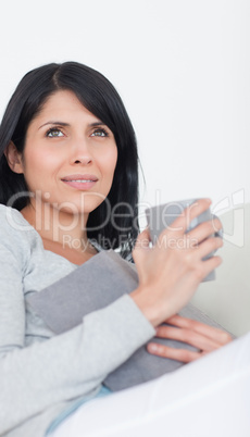 Woman holding a book and a grey mug