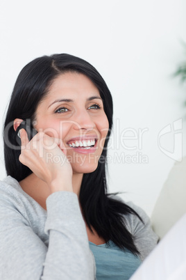 Woman with a phone next to her ear sitting on a couch