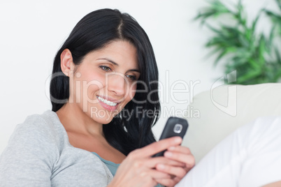 Woman holding a phone with two hands while sitting on a couch