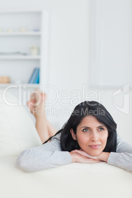 Woman holding her head with two hands while resting on a couch