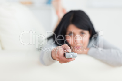 Woman holding a remote while lying on a sofa