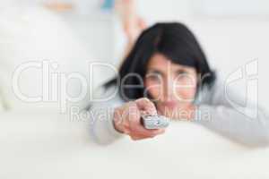 Woman holding a remote while lying on a sofa