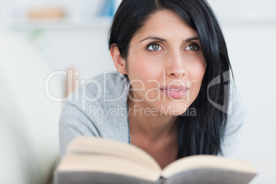 Woman with a book on her hands lying on a sofa