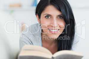 Woman smiling while holding a book in a couch