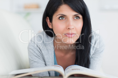 Woman holding a book in her hands while lying on a couch