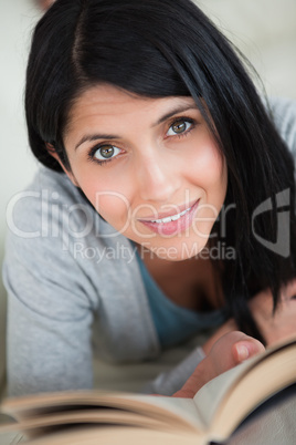 Woman holding a book while resting on a white sofa