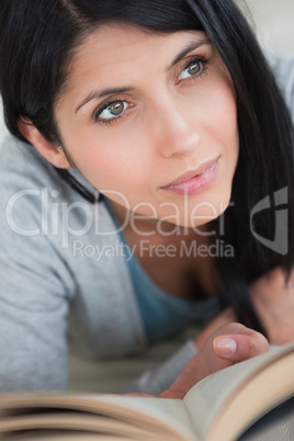 Woman holding up a book while lying on a sofa