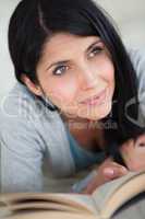 Woman holding a book and lying on a sofa