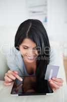 Woman smiling and holding a card while touching a tablet