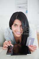 Woman smiling while holding a credit card and touching a tablet