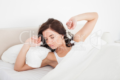 Brunette woman stretching her arms while lying