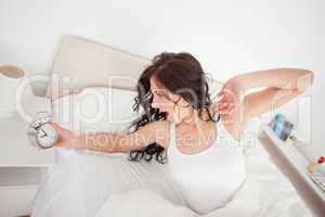 Tired woman holding her alarm clock