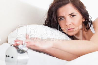 Serious woman switching off her alarm clock