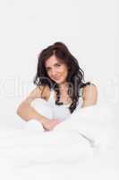 Calm brunette woman sitting in her bed