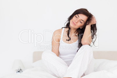 Peaceful brown-haired woman sitting on her bed