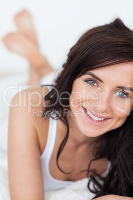 Smiling brunette woman lying on her quilt