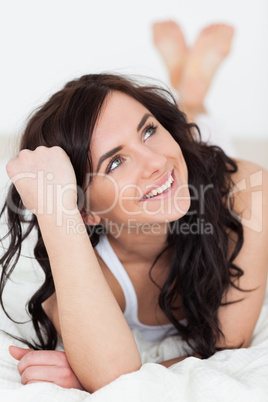 Smiling woman thinking while lying on her bed