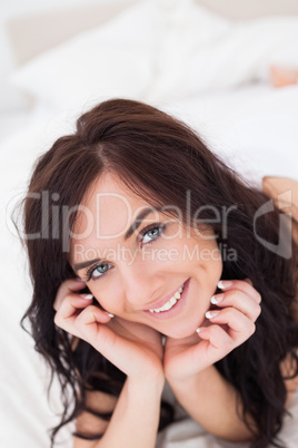 Joyful woman lying on her bed in the morning
