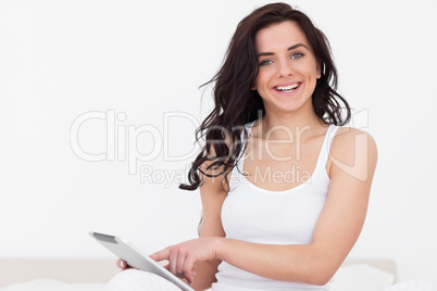 Smiling brunette woman sitting while touching her tablet pc