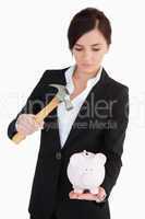 Woman in suit  going to break a piggy-bank