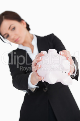 Woman in suit emptying a piggy-bank