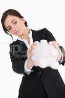 Woman in black suit emptying a piggy bank