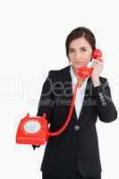 Businesswoman using a red dial telephone