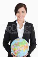 Smiling woman in suit holding an earth globe