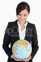 Brunette woman in suit holding an earth globe