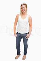 Happy blonde woman standing with her thumbs in her pockets