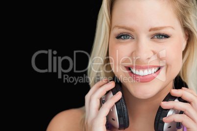 Smiling woman standing while holding her headphones