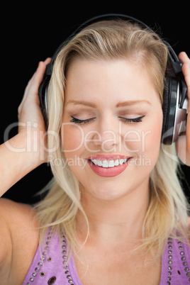 Joyful blonde woman wearing her headphones
