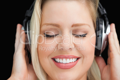 Cheerful woman closing her eyes while listening to music