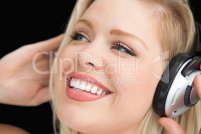 Happy blonde woman listening to music through headphones