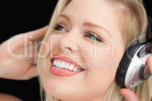 Happy blonde woman listening to music through headphones