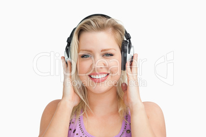 Smiling blonde woman placing her hands on her headphones