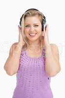Happy blonde woman placing her hands on her headphones