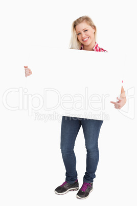 Blonde woman beaming while pointing at a placard
