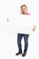 Blonde woman beaming while pointing at a placard