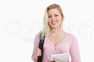 Blonde woman holding a tablet computer and a shoulder bag