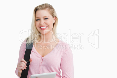 Smiling blonde woman holding a shoulder bag with a tablet pc