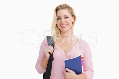 Blonde woman standing while holding notebooks