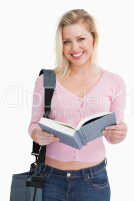 Happy blonde woman holding a novel and her shoulder bag