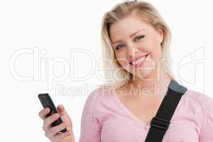 Blonde woman holding her mobile phone while writing a text